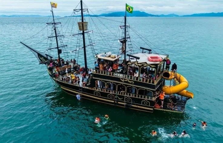 Vista aérea do barco pirata com toboágua amarelo e gente na água